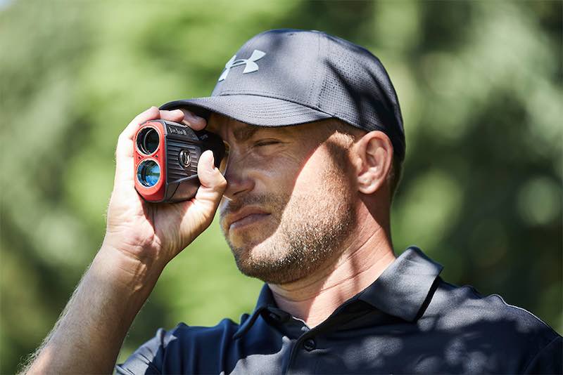 Golfer using a Bushnell rangefinder to figure out what club to use.